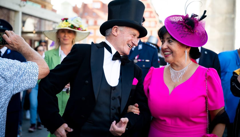 Dwoje ludzi uśmiecha się do siebie - pan w cylindrze, pani w toczku