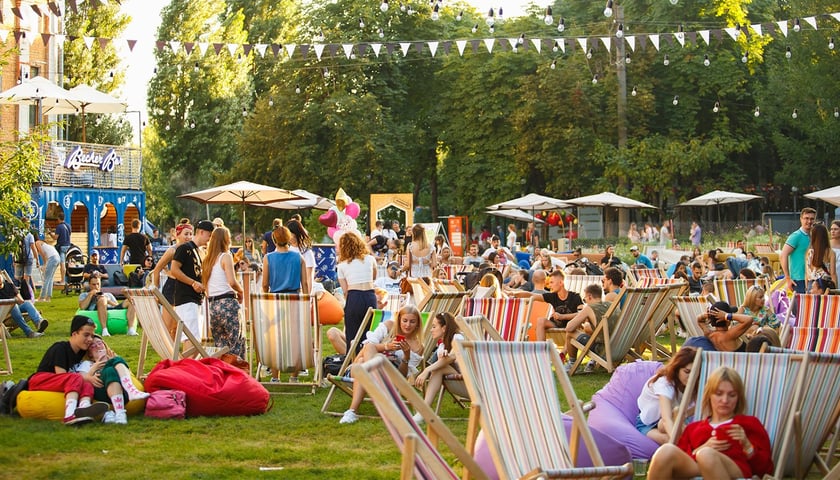 Impreza plenerowa. Na zdjęciu widać ludzi siedzących w leżakach na trawniku. Zdjęcie ilustracyjne