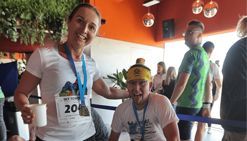 Kobieta i zmęczony mężczyzna w stroju sportowym odpoczywający po biegu. Uczestnicy Sky Tower Run z 2024 roku.