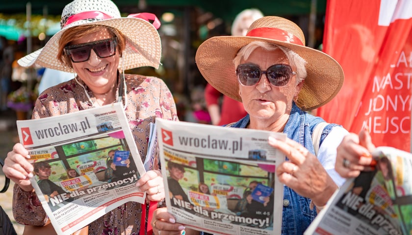 Dwie seniorki w kapeluszach z biuletynem Wroclaw.pl podczas Wrocławskich Dni Seniora na pl. Solnym