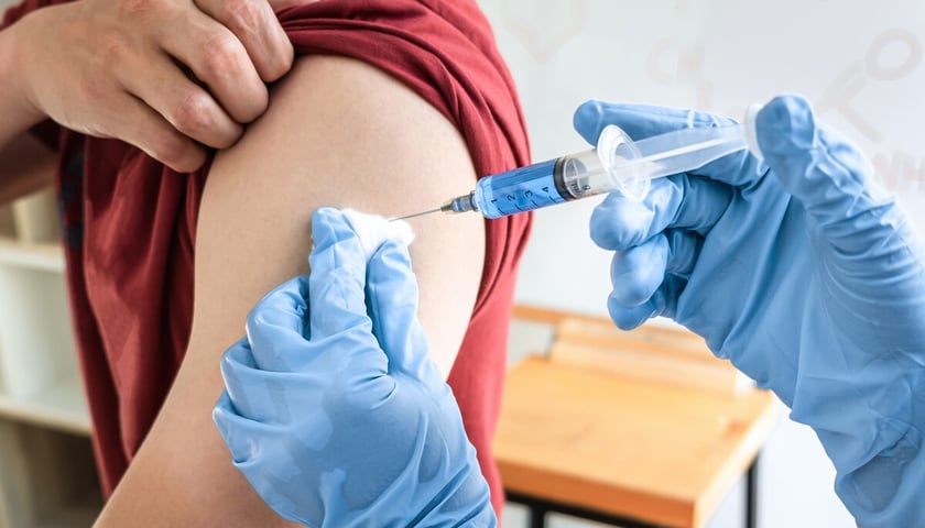 Na zdjęciu widać moment szczepienia, rękę pacjenta i dłonie ze strzykawką