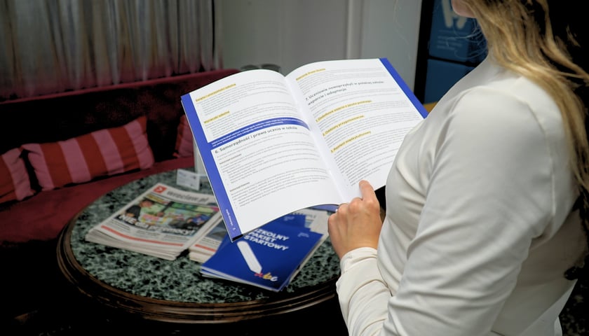 Uczennica trzymająca w rękach „Szkolny pakiet startowy”