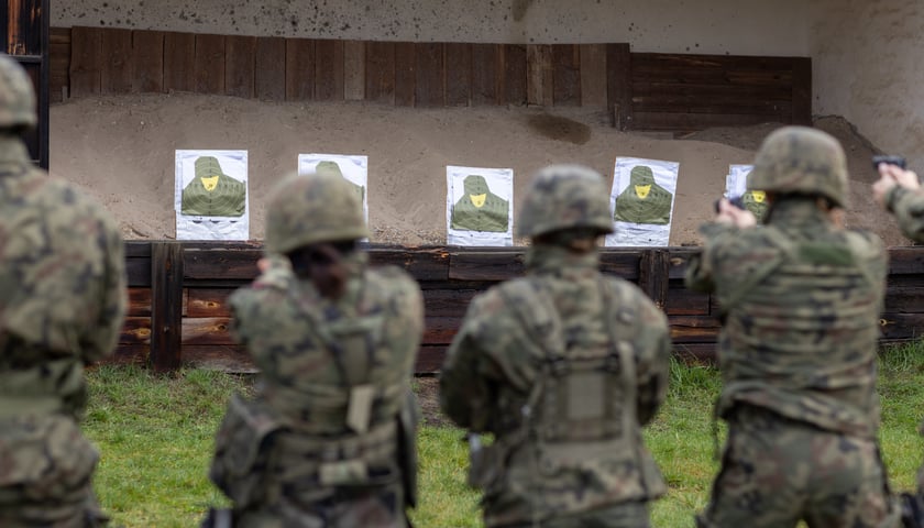 Czterech żołnierzy w pełnym rynsztunku strzela do tarcz