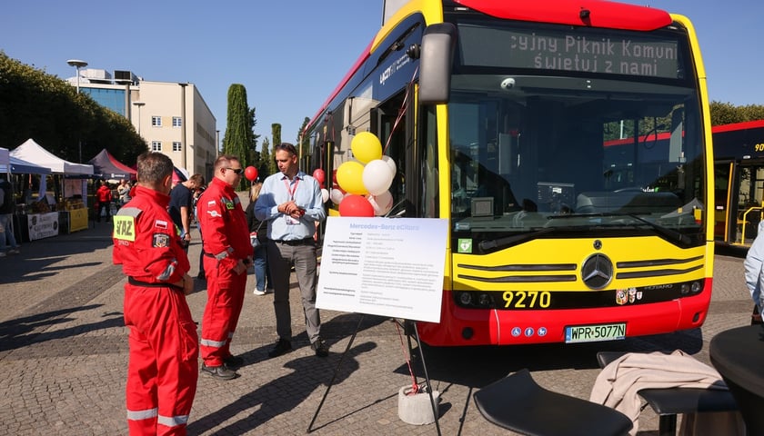 Aglomeracyjny Piknik Komunikacyjny. Na zdjęciu nowoczesny autobus i kilka osób przy nim, które rozmawiają