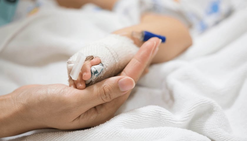 Na zdjęciu widać dłoń dziecka z opatrunkiem w dłoni dorosłej osoby. Zdjęcie ilustracyjne