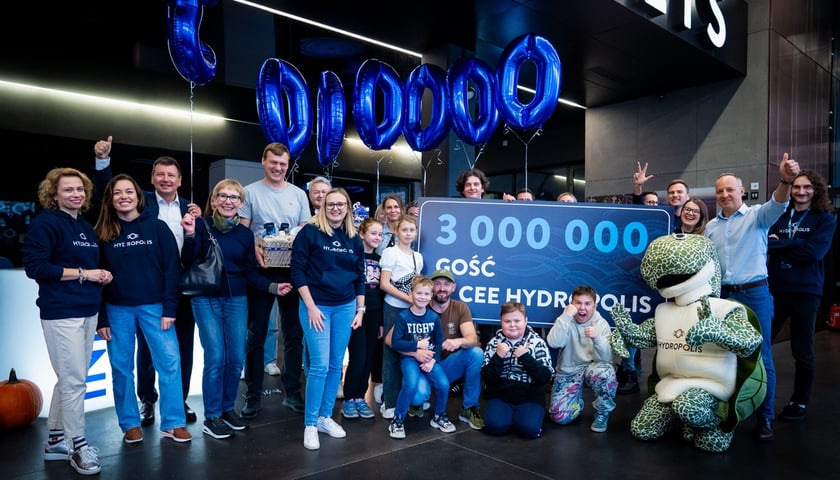 Powitanie trzymilionowego gościa w Hydropolis we Wrocławiu. na zdjęciu grupa uśmiechniętych osób, między którymi jest tablica z napisem "3 000 000 CEE Hydropolis"