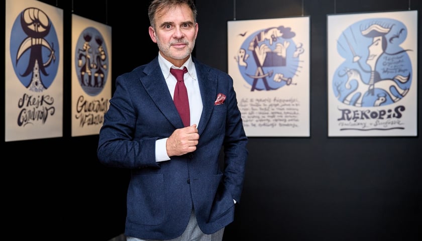 Wrocławski rysownik Tomasz Broda na tle swoich prac "Rękopis znaleziony we Wrocławiu"