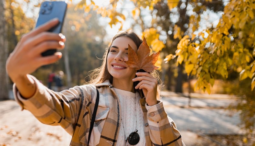 Uśmiechnięta kobieta robiąca sobie zdjęcie w parku, zdjęcie ilustracyjne