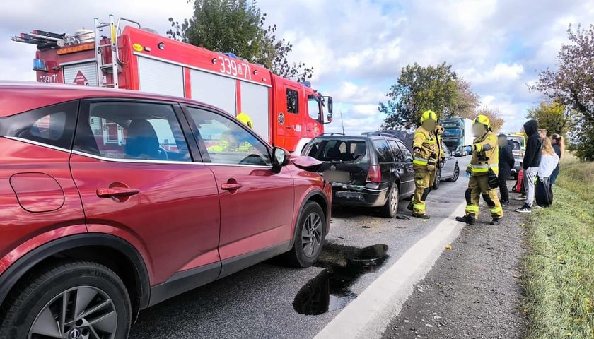 Na zdjęciu uszkodzone samochody osobowe, grupa cywilów i strażaków