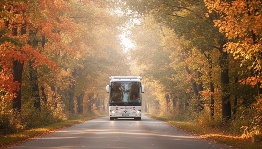 Krwiobus Regionalnego Centrum Krwiodawstwa i Krwiolecznictwa na drodze wśród jesiennych drzew.