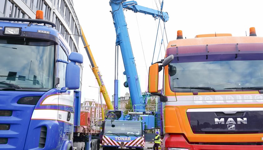 Samochody ciężarowe z dźwigiem przy  biurowcu. Prace na dachu Grunwaldzki Center przy rondzie Reagana.