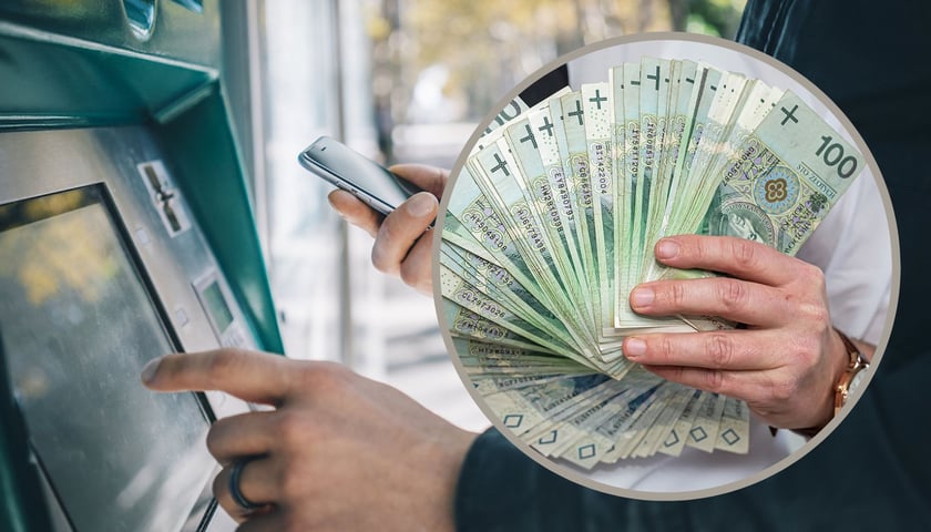 Mężczyzna przy bankomacie, w ręku ma telefon, w tle plik banknotów, zdjęcie ilustracyjne