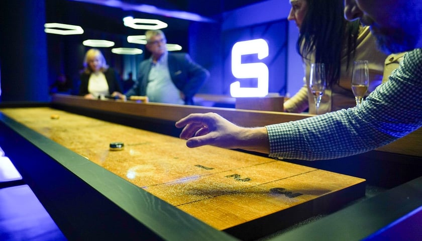 Gracze przy stole do shuffleboarda, wieczór zapowiadający otwarcie Sky Games