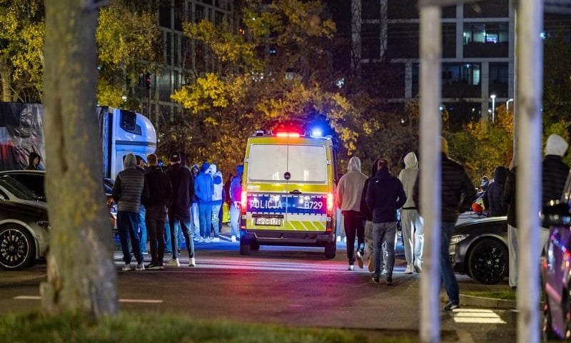 Radiowóz na sygnałach świetlnych, wokół niego zgromadzeni ludzie