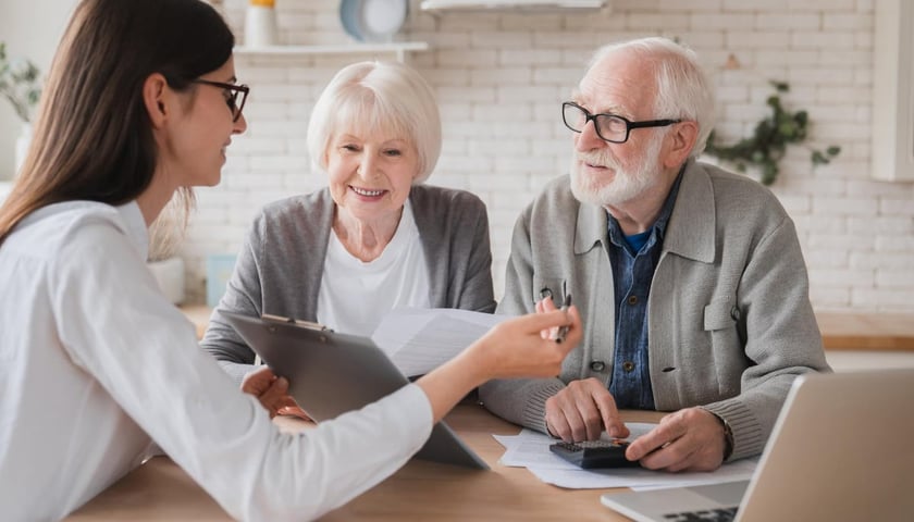 Młody i starszy mężczyzna, w dłoniach mają dokumenty i patrzą na kalkulator na stole, zdjęcie ilustracyjne