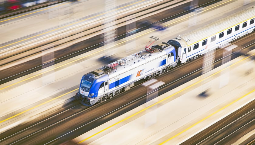 Pociąg osobowy w trakcie jazdy przez stację, widok z lotu ptaka.