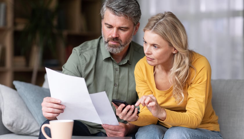 Kobieta i mężczyzna siedzą na kanapie i patrzą na dokumenty