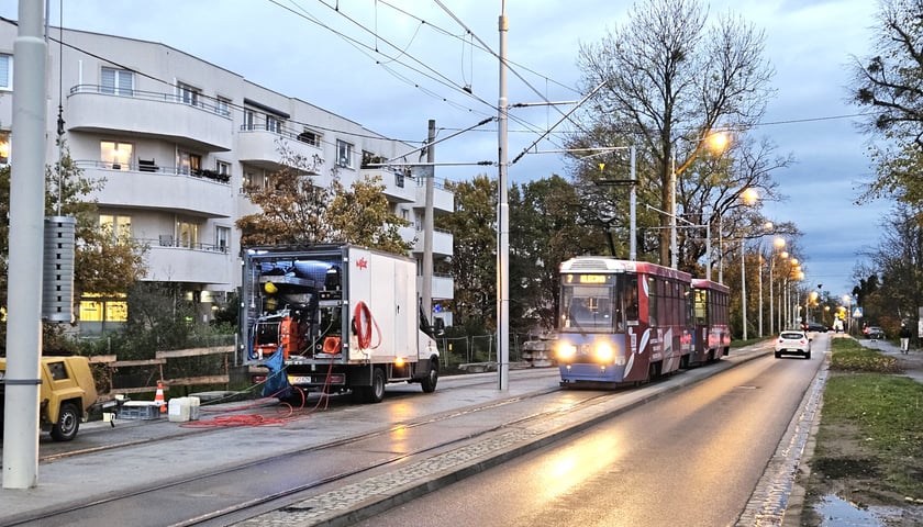 Tramwaj jadący torem obok mijanki, na której stoi pojazd techniczny. Torowisko na ul. Przyjaźni. 
