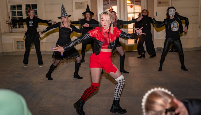 Grupa ludzi przebrana za czarownice i duchy tańczy przed zamkiem. Halloween w OPT Leśnica.