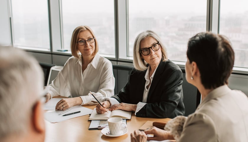 Zdjęcie ilustracyjne: siedzący przy stole ludzie, którzy wspólnie nad czymś pracują