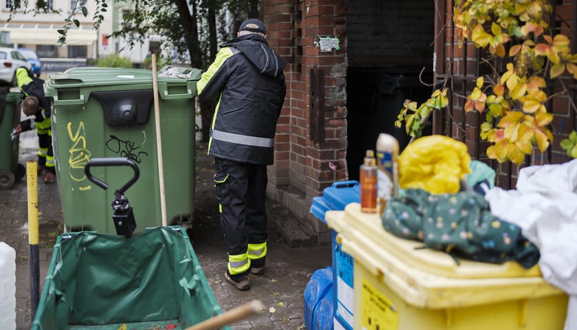 Pracownik Wrocławskiej Sp&oacute;łdzielni Socjalnej sprzątający miejsce gromadzenia odpad&oacute;w