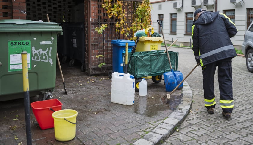 Pracownik Wrocławskiej Spółdzielni Socjalnej sprzątający miejsce gromadzenia odpadów