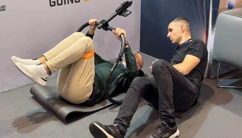 Dwóch mężczyzn leży na ziemi - twórca startupu BackApp (tryVinci) pokazuje klientowi jak działa jego produkt