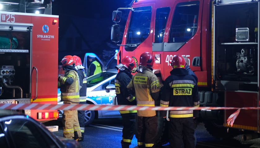 Strażacy podczas nocnej akcji, w tle wozy, zdjęcie ilustracyjne