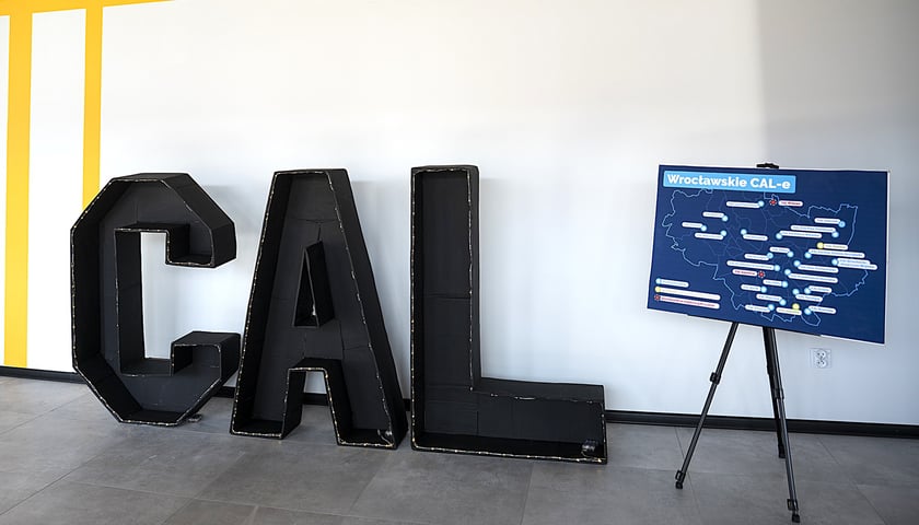 Litery CAL stojące na podłodze przy ścianie, obok mapa z wrocławskimi CAL-ami