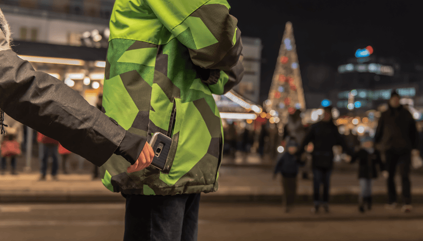 Człowiek wyciąga z kieszeni innej osoby portfel, w tle centrum miasta w świątecznej odsłonie