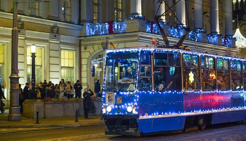 Tramwaj ozdobiony światełkami jedzie ulicą koło Opery.