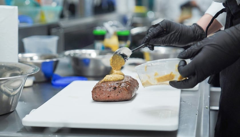 Jedno z konkursowych dań na talerzu i dłonie kucharza, 5 grudnia 2025