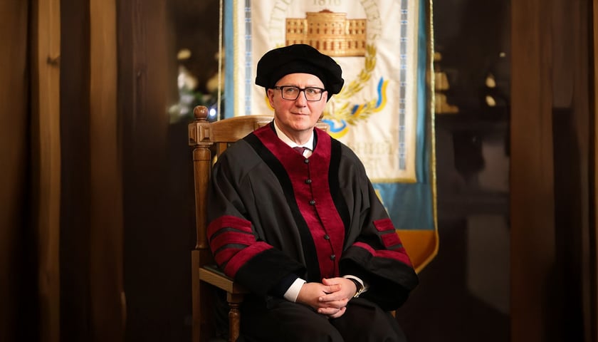 Prof. Arkadiusz Wójs, rektor Politechniki Wrocławskiej podczas uroczystości nadania tytułu doktora honoris causa Politechniki Lwowskiej. Na zdjęciu mężczyzna w torze i birecie siedzi w fotelu 