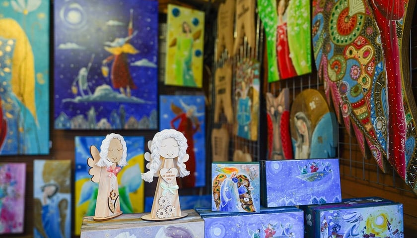 Stoisko na jarmarku bożonarodzeniowym. Zdjęcie ilustracyjne. Na zdjęciu ceramiczne aniołki i kolorowe obrazki