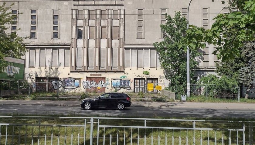 Budynek po kinie Lwów i przejeżdżający samochód, maj 2024