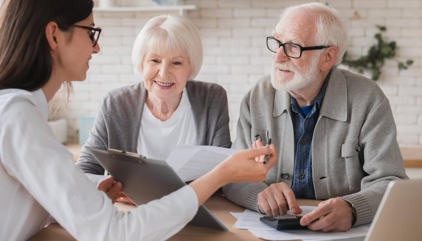 Zdjęcie ilustracyjne: przy stole siedzi młoda kobieta, starsza kobieta i starszy mężczyzna