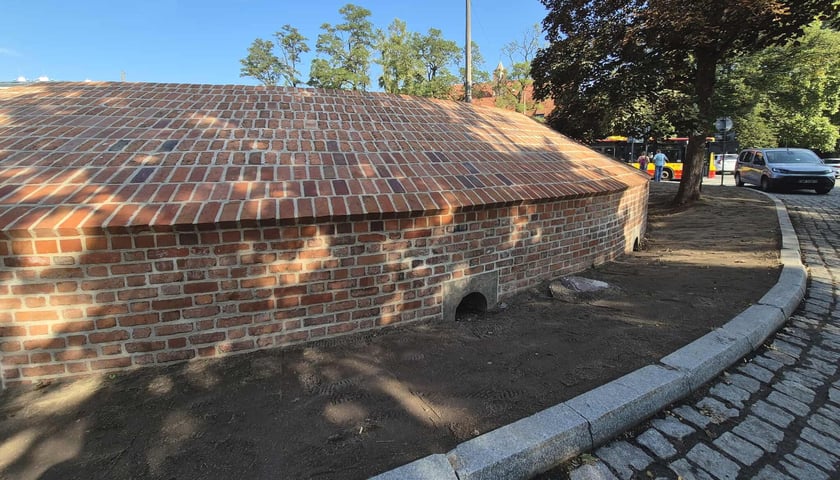 Widok na ceglaną fortyfikację i chodnik, w tle drzewa - Basteja Hioba przy Alei Słowackiego. 