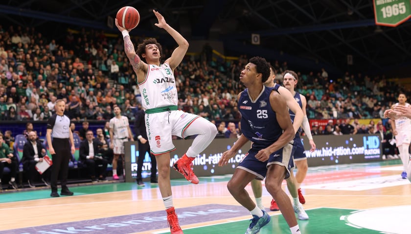 Zawodnik w wyskoku z piłką do koszykówki, obok inni gracze na parkiecie. Mecz Śląska Wrocław w hali Orbita - zdjęcie ilustracyjne.