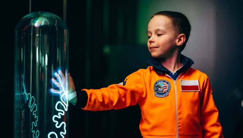 Chłopiec w kombinezonie astronauty podczas zwiedzania wystawy Kosmopark