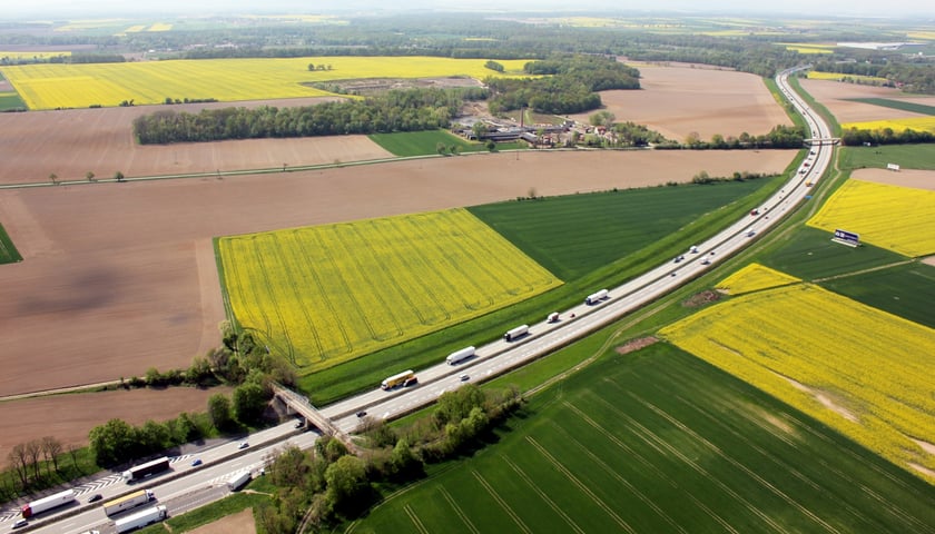 Widok na dwujezdniową drogę biegnącą przez pola z lotu ptaka. Odcinek A4 na Dolnym Śląsku.