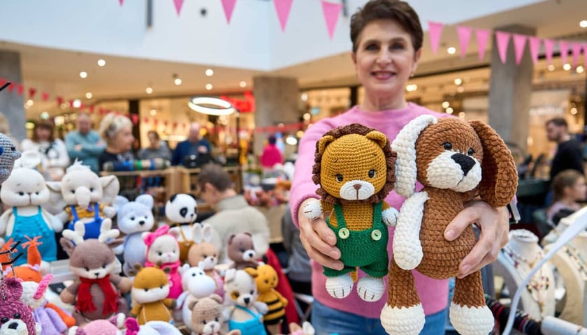 Uśmiechnięta kobieta prezentująca dwie szydełkowe maskotki, targi Artishop 17.01.2026 r.
