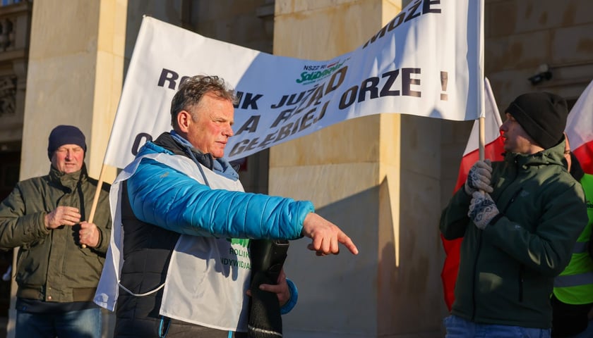 Osoba w białej kamizelce na tle transparentu pod urzędem wojewódzkim, 20 stycznia 2026 roku