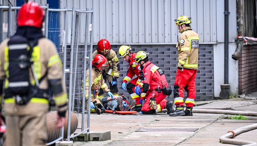 Ratownicy OSP GRS Starówka podczas akcji. Na zdjęciu osoby w mundurach strażaków pochylają się nad leżącym mężczyzną