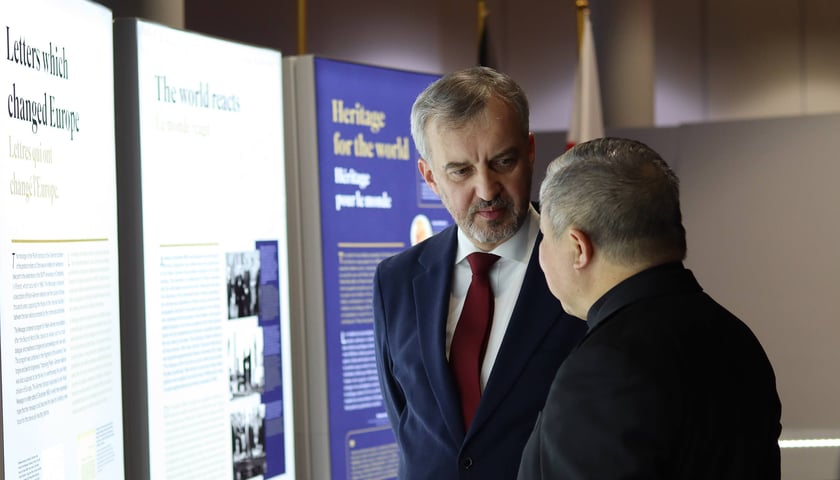 Dwóch mężczyzn w rozmowie przy planszach wystawy w PE