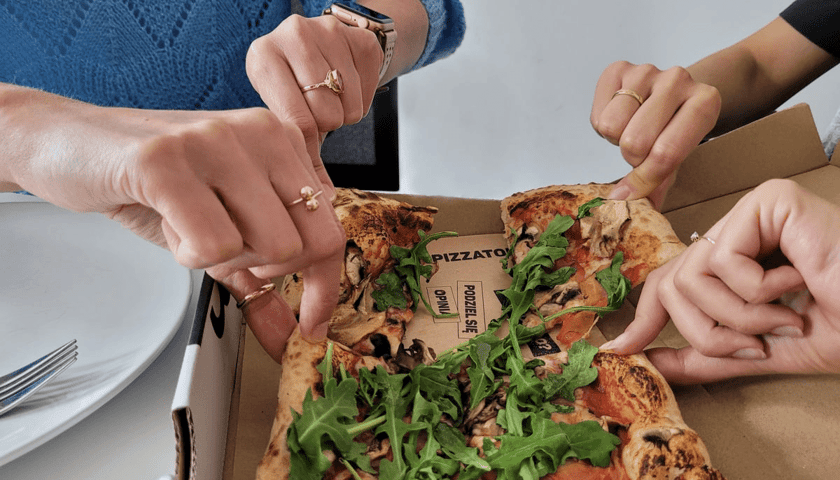 Na zdjęciu ludzie dzielący się pizzą z restauracji Pizzatopia we Wrocławiu. Sprawdź, jakie inne restauracje i kawiarnie otworzyły się w stolicy Dolnego Śląska!