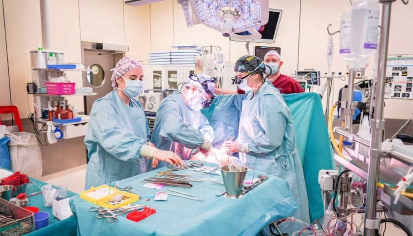 Na zdjęciu sala operacyjna podczas zabiegu. Wokół stołu operacyjnego stoją osoby w odzieży ochronnej