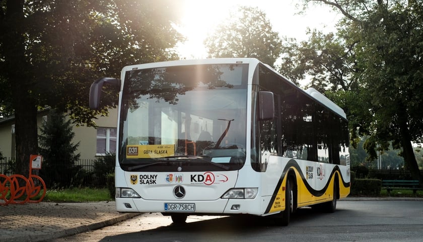 Autobus zastępczy w barwach Kolei Dolnośląskich na przystanku - zdjęcie ilustracyjne.