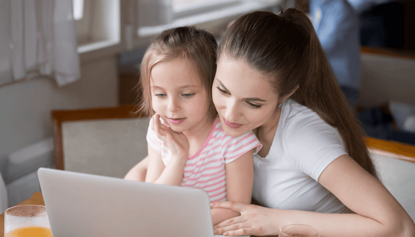 Zdjęcie ilustracyjne - młoda kobieta z dziewczynką siedzą przy otwartym laptopie.
