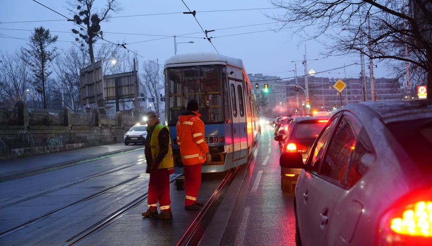 Służby pracują przy naprawie zerwanej sieci na Pułaskiego - 6.02. Z tyłu tramwaj.