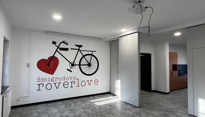 Wnętrze Stanicy Rowerowej w Żmigrodzie. Na zdjęciu pomieszczenie w budynku z grafiką na ścianie prezentującą zarys roweru